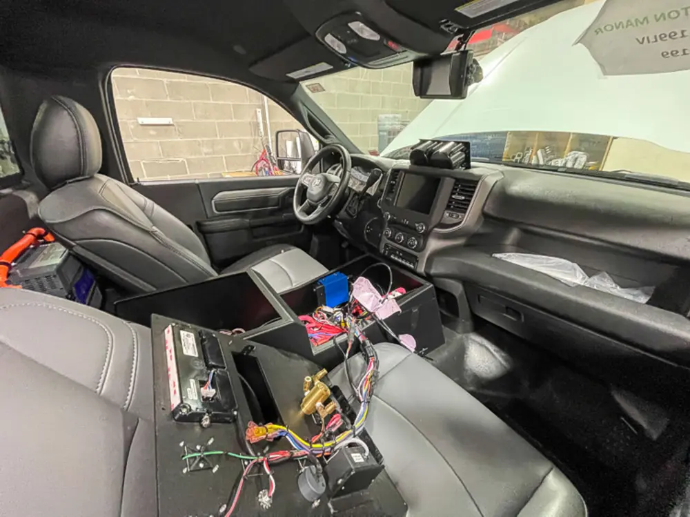 Exterior view of small fire truck showing cab, body compartments, and wheel/tire area.
